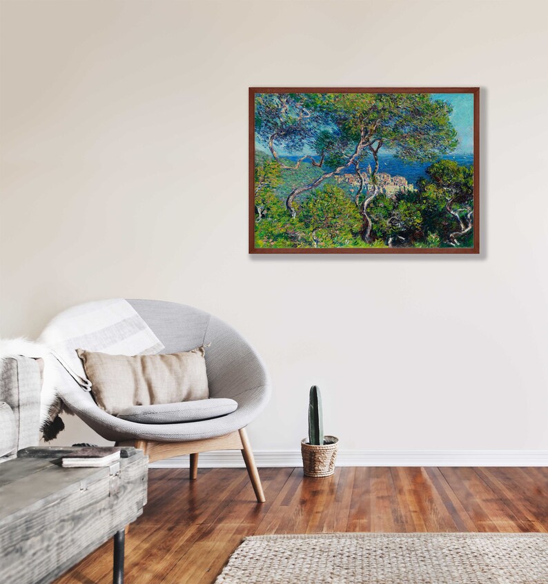 May include: A framed painting of a landscape scene with a view of a town from a hilltop. The painting is done in a style reminiscent of Impressionism, with visible brushstrokes and a focus on light and color. The scene is dominated by a lush green forest in the foreground, with a glimpse of a blue sea and a town in the distance.