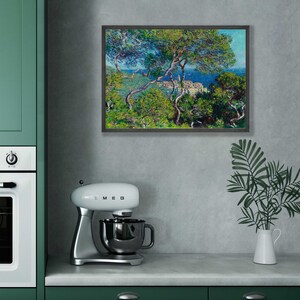 May include: A framed painting of a seascape with a view of a town nestled among trees. The painting is in a dark wood frame and is hanging on a gray wall.