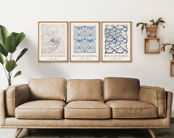 May include: A set of three framed wall art prints featuring William Morris designs. Each print displays intricate botanical patterns in blue and cream tones, with the text William Morris printed at the bottom of each individual rectangular frame.