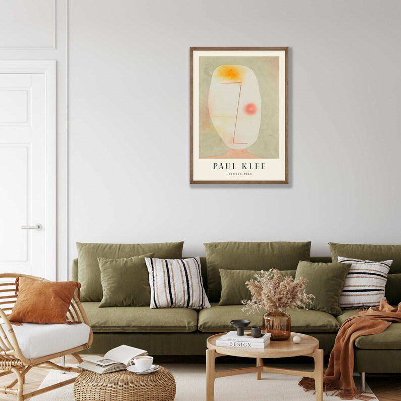 May include: A framed art print featuring a Paul Klee painting titled Untitled, 1934. The artwork displays an abstract, pale oval shape with a soft yellow top, a thin red line, and a small red circle against a muted green background.