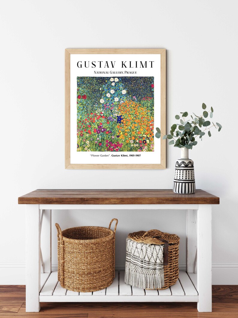 Op de afbeelding: Een ingelijste print van een schilderij van Gustav Klimt getiteld "Bloementuin". Het schilderij toont een levendig veld met bloemen in verschillende kleuren, waaronder rood, geel, oranje, roze en paars. Het schilderij wordt getoond aan een witte muur met een houten lijst.