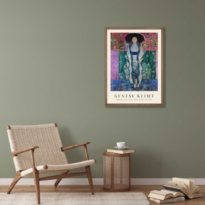 Pu&ograve; includere: Un poster incorniciato di un dipinto di Gustav Klimt intitolato "Ritratto di Adele Bloch-Bauer, 1912". Il dipinto raffigura una donna con un lungo abito fluido su uno sfondo colorato.