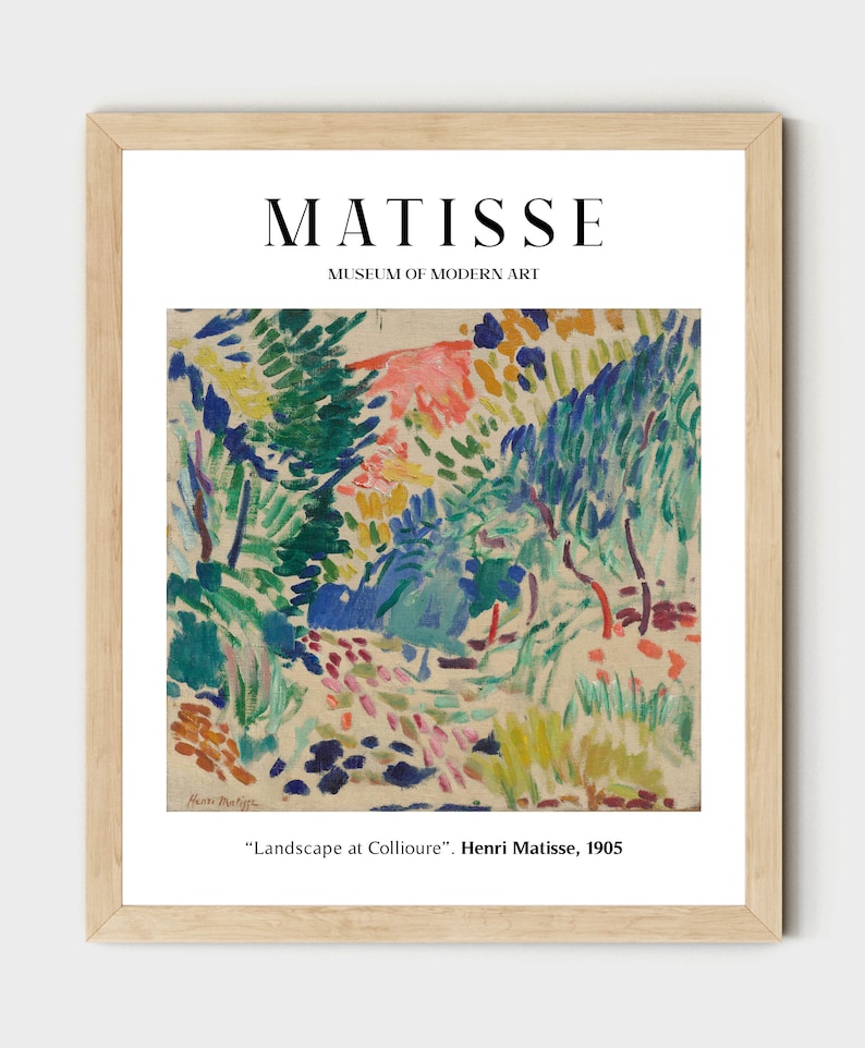 May include: A framed print of a painting by Henri Matisse titled "Landscape at Collioure". The painting features a colorful landscape with green trees, blue sky, and pink flowers. The print is framed in a light wood frame.