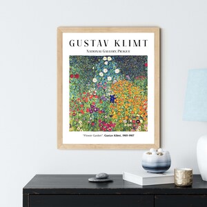 Op de afbeelding: Een ingelijste print van een schilderij van Gustav Klimt getiteld "Bloementuin". Het schilderij toont een levendig veld met bloemen in verschillende kleuren, waaronder rood, geel, oranje, blauw en groen. Het schilderij is ingelijst in een houten lijst met een witte passe-partout.