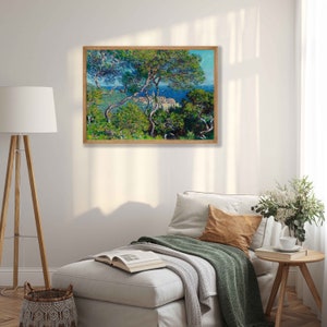 May include: A painting of a seascape with a town in the distance, seen through a grove of trees. The trees are painted in a vibrant green, with the water a bright blue. The sky is a pale blue, with white clouds.