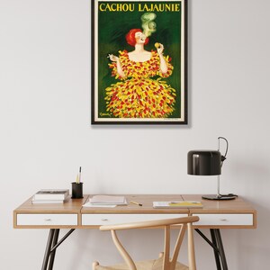 May include: Vintage poster advertising Cachou Lajaunie, a brand of breath mints. The poster features a woman in a yellow and red dress smoking a cigarette. The text "CACHOU LAJAUNIE" is printed in black at the top of the poster.