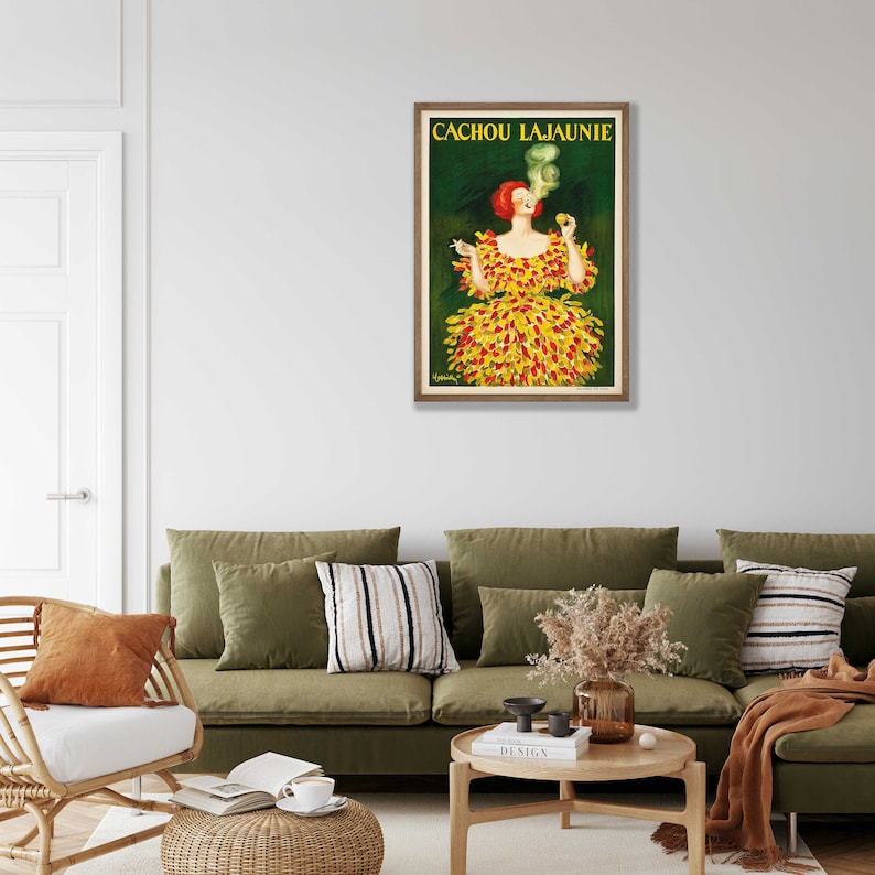 May include: Vintage poster advertising Cachou Lajaunie, a French brand of breath mints. The poster features a woman in a yellow and red dress, smoking a cigarette and holding a box of Cachou Lajaunie.