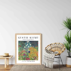 Op de afbeelding: Een ingelijste print van een schilderij van Gustav Klimt getiteld "Bloementuin". Het schilderij toont een levendige tuinsc&egrave;ne met een verscheidenheid aan bloemen in tinten geel, oranje, rood, blauw en wit. Het schilderij wordt getoond op een witte muur met een houten vloer.
