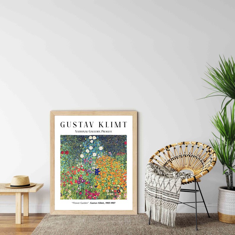 Op de afbeelding: Een ingelijste print van een schilderij van Gustav Klimt getiteld "Bloementuin". Het schilderij toont een levendige tuinsc&egrave;ne met een verscheidenheid aan bloemen in tinten geel, oranje, rood, blauw en wit. Het schilderij wordt getoond op een witte muur met een houten vloer.
