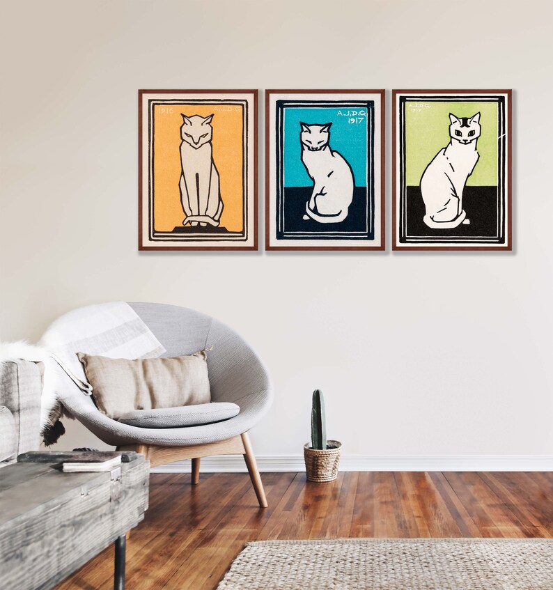 May include: Three framed prints of white cats in different poses. The cats are on a yellow, blue, and green background. The frames are brown wood.