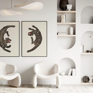 May include: Two black and white stylized illustrations of dogs in a fighting pose, framed and hung on a white wall. The illustrations are in a minimalist style and feature bold lines.