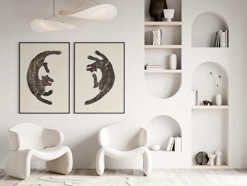 May include: Two black and white stylized illustrations of dogs in a fighting pose, framed and hung on a white wall. The illustrations are in a minimalist style and feature bold lines.