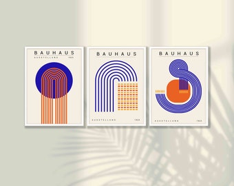 May include: A set of three rectangular wall art prints featuring Bauhaus Ausstellung 1923 text. Each print displays geometric designs with blue, orange, and cream colors, including concentric arches, grid patterns, and circular shapes on a light background.