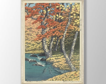 May include: A woodblock print of a Japanese landscape with a river flowing through a forest of trees with red, orange, and yellow leaves. The print is framed in a light wood frame.