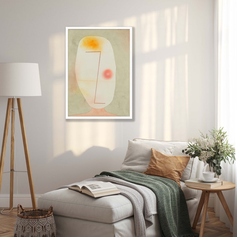 May include: A framed wall art print featuring an abstract, pale oval head shape against a muted sage green background. The figure includes a soft yellow patch at the top, a single red circular dot on the right, and a thin, angular red line.