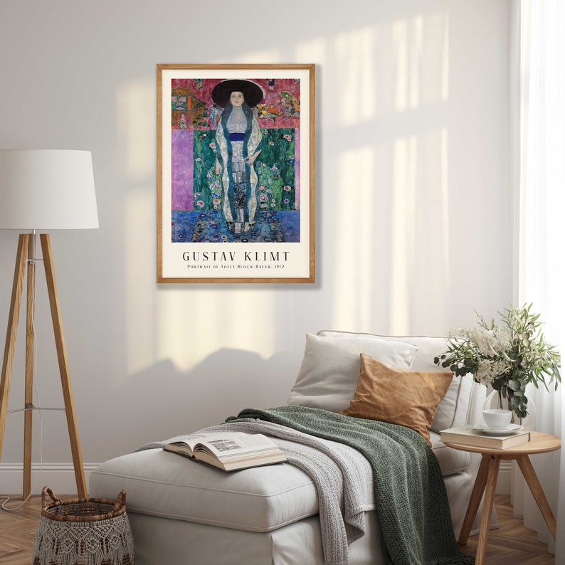 Pu&ograve; includere: Un poster incorniciato di un dipinto di Gustav Klimt intitolato "Ritratto di Adele Bloch-Bauer I" (1907). Il dipinto raffigura una donna con un lungo abito bianco e un cappello nero, in piedi su uno sfondo colorato di forme geometriche e motivi floreali.