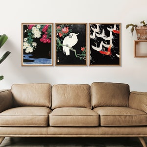 K&ouml;nnte beinhalten: Drei gerahmte japanische Drucke mit schwarzem Hintergrund. Der linke Druck zeigt wei&szlig;e und rosa Blumen, der mittlere Druck zeigt einen wei&szlig;en Vogel auf einem Zweig mit roten Blumen und der rechte Druck zeigt rote und wei&szlig;e V&ouml;gel, die in einer Schar fliegen.