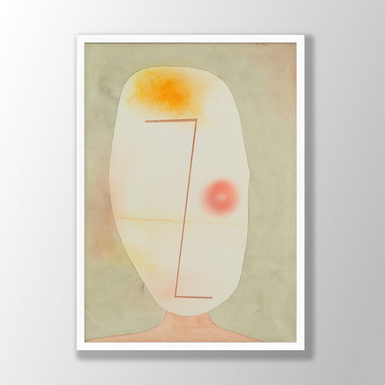 May include: A framed abstract art print featuring an oval-shaped off-white head against a muted sage green background. The face includes a single red circular spot, a thin brown angular line, and a soft yellow wash at the top, set in a white frame.