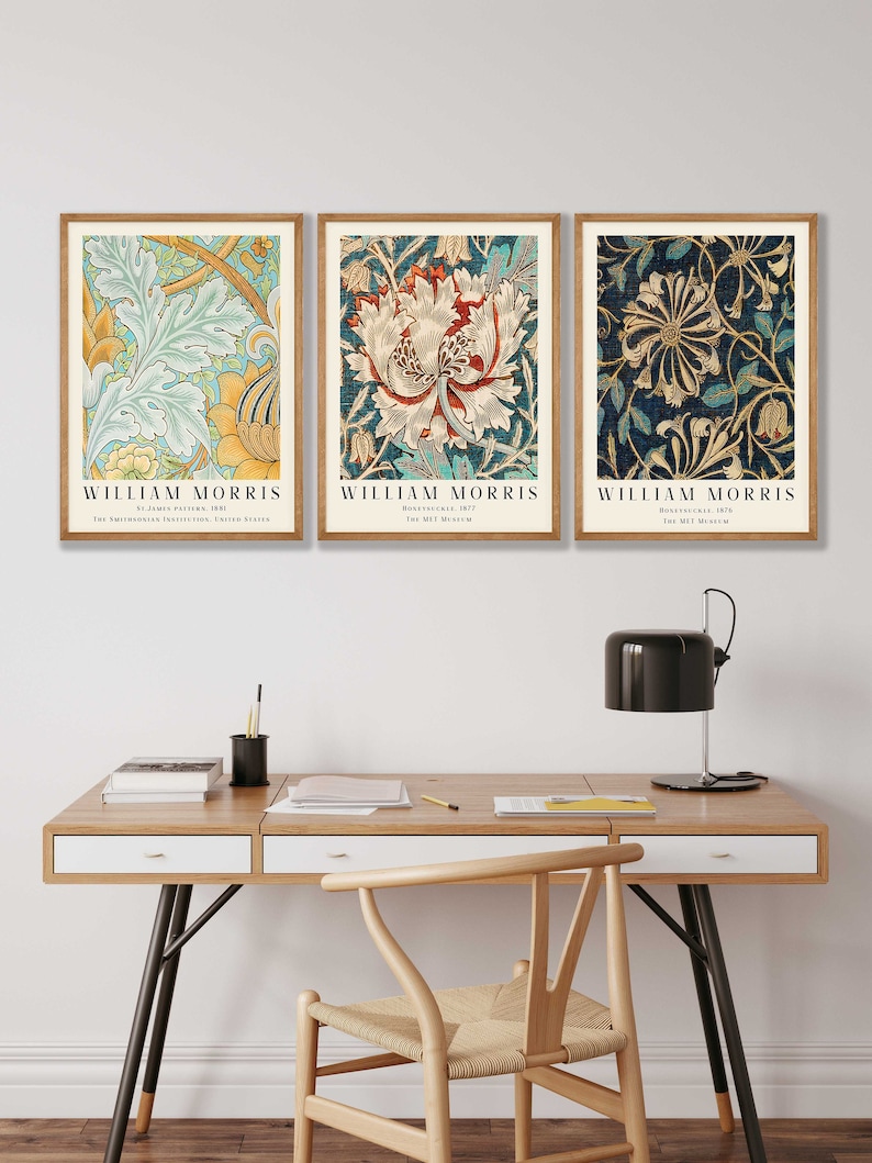 May include: Three framed prints of floral patterns by William Morris. The prints are in a modern home office setting with a wooden desk, chair, and lamp.