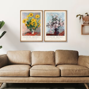 May include: Two framed art prints of paintings by Claude Monet. The left print features a vase of sunflowers, while the right print shows a vase of white flowers. Both prints have a white background and a red and brown table.