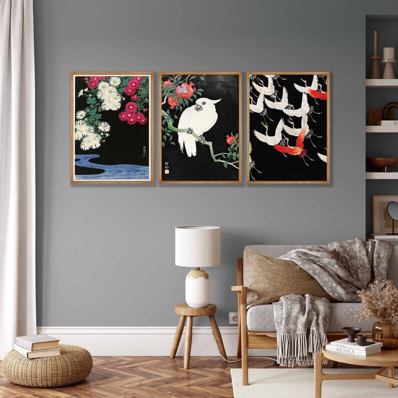 K&ouml;nnte beinhalten: Drei gerahmte Drucke mit schwarzen Hintergr&uuml;nden und japanischem Kunststil. Der linke Druck zeigt wei&szlig;e und rosa Blumen mit einem blauen Wasserlauf. Der mittlere Druck zeigt einen wei&szlig;en Kakadu, der auf einem Ast mit roten Blumen sitzt. Der rechte Druck zeigt wei&szlig;e Kraniche mit roten Akzenten, die in Formation fliegen.