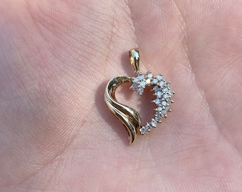 May include: A gold heart-shaped pendant with a swirl design and a border of small diamonds.