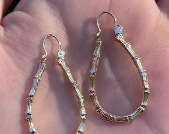 May include: A pair of gold-tone teardrop-shaped earrings with a bamboo-like design.