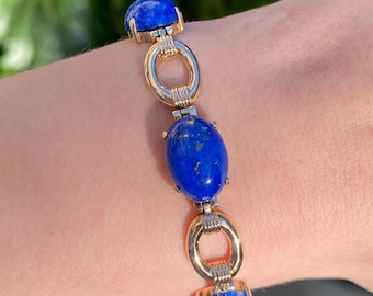 May include: A gold bracelet with oval-shaped lapis lazuli stones. The bracelet has a chain link design with circular links.