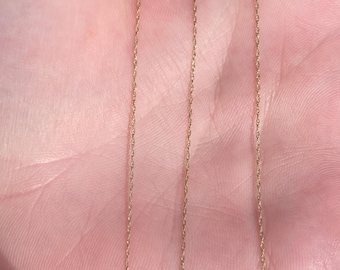 May include: A gold chain necklace with a delicate, twisted design. The chain is approximately 18 inches long.