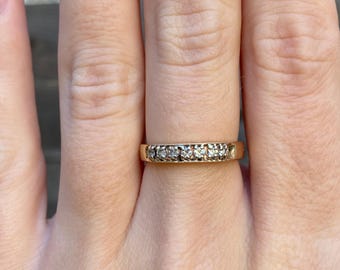 May include: A thin gold band ring with a row of small diamonds.