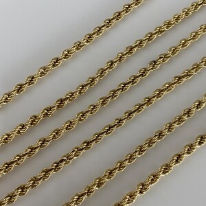 Puede incluir: Primer plano de varias cadenas de cuerda de color dorado. Las cadenas est&aacute;n dispuestas en diagonal sobre un fondo blanco. Las cadenas tienen un dise&ntilde;o de cuerda trenzada, y el color dorado es brillante y reluciente. Las cadenas son probablemente joyas.