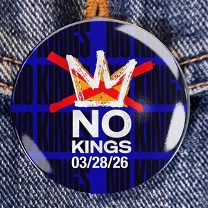 Pode incluir: Um botão redondo com fundo azul e as palavras "NO KINGS" em branco. Uma coroa dourada e branca é riscada com linhas vermelhas. A data "03/28/26" é impressa abaixo da palavra "KINGS".