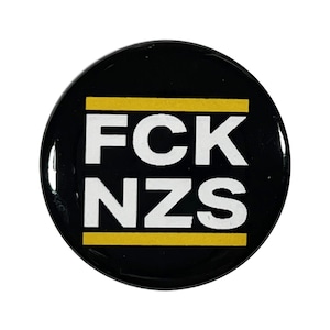 May include: A black and yellow button with the text "FCK NZS" in white letters.