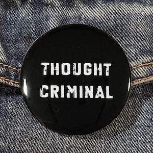 May include: A black button with white text that reads "Thought Criminal".