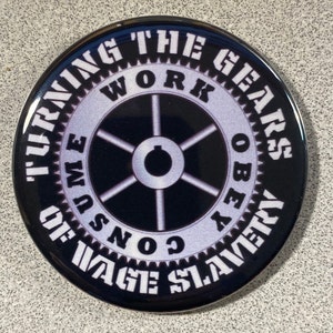 May include: A black and white button with the text "Turning the Gears of Wage Slavery Work Obeys Consume" around a stylized gear with a circle in the center.