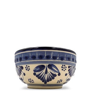 May include: A ceramic bowl with a cream-colored base and intricate blue floral patterns. The rim features a dark blue band with a repeating design. The bowl's exterior is adorned with stylized leaves and small floral clusters.