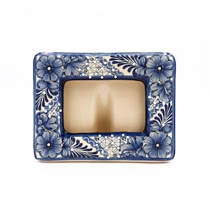 May include: Rectangular ceramic photo frame with a cream-colored interior. The frame is decorated with blue floral and leaf patterns, with white and gray accents. The frame has rounded corners and a glossy finish.