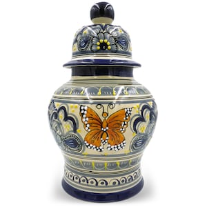 May include: A ceramic jar with a lid, featuring a hand-painted butterfly design. The jar is adorned with blue, yellow, and gray floral patterns. The butterfly is orange with white spots. The jar is a decorative piece.