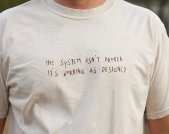 The system isn't broken, it's working as designed/ Social commentary streetwear/ statement Unisex T-shirt.