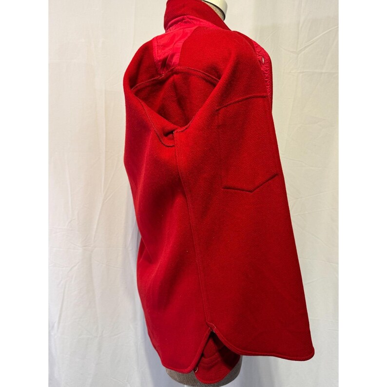 May include: A vibrant red wool coat with a high collar and a tailored fit. The coat features a pocket on the front and a split hem. The coat is displayed on a mannequin against a white backdrop.