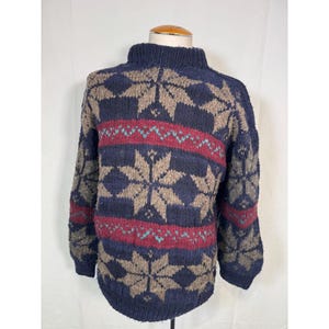 May include: A blue knitted sweater with a brown and red snowflake pattern.