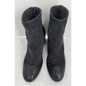 May include: A pair of black suede ankle boots. The boots have a rounded toe and a zip closure at the back. The boots are approximately 15 cm tall.