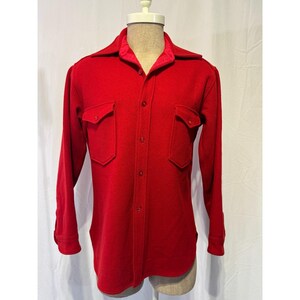May include: A bright red long-sleeve shirt with two chest pockets and a button-down front. The collar has a contrasting red satin lining. The shirt is displayed on a mannequin.