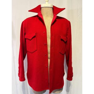 May include: A vibrant red wool shirt jacket with two front pockets and a wide collar. The jacket has long sleeves with buttoned cuffs and a button-up front. The jacket is displayed on a mannequin.