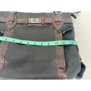 May include: Black leather handbag with brown crocodile-textured accents. The bag features a silver-tone buckle and hardware. The measurement across the top is approximately 12 inches.