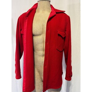 May include: A vibrant red wool shirt jacket with a collared neckline and button-down closure. Features a single chest pocket and a satin lining along the open front. The long sleeves have buttoned cuffs.