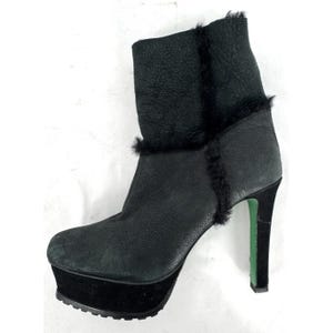May include: A black ankle boot with a textured leather upper and black fur trim along the seams. The boot features a thick black platform sole and a high stiletto heel with a bright green inner lining visible on the side of the heel.