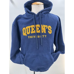 May include: A navy blue hooded sweatshirt featuring the text QUEEN'S UNIVERSITY in yellow block lettering across the chest. The hoodie includes a front kangaroo pocket, long sleeves, and matching navy blue drawstrings at the neckline.