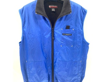 Puede incluir: Un chaleco azul sin mangas con una cremallera negra y un forro de polar negro. El chaleco tiene un pequeño bolsillo en el lado derecho con el texto "Polo Jeans Company" en blanco.