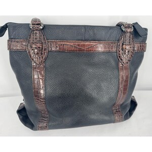 May include: Black leather tote bag with brown crocodile-textured accents. The bag features a zip closure and decorative buckles. The bag has a textured leather exterior and a structured shape.